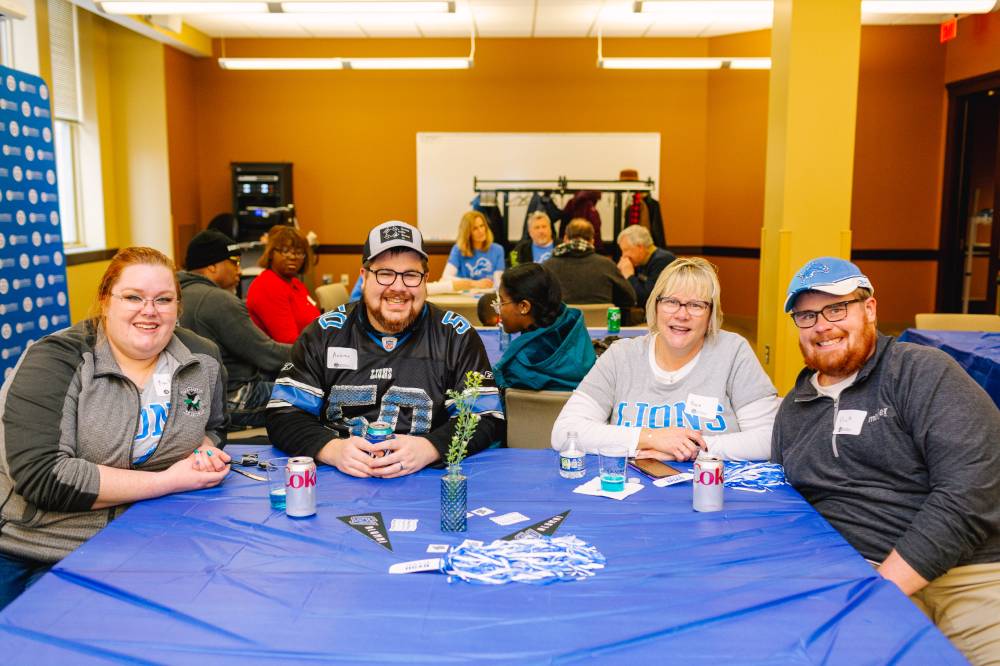 A family poses for a group photo at a table during the tailgate party